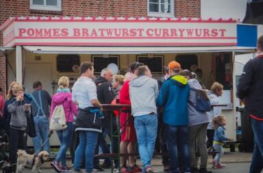 Deutsche vor einem Pommes-, Bratwurst-Stand