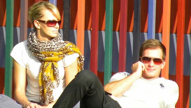 junges Paar mit Sonnenbrillen, sie sitzend, er liegend