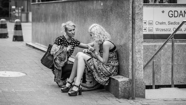 zwei Frauen vor U-Bahn-Eingang, eine tröstet die andere